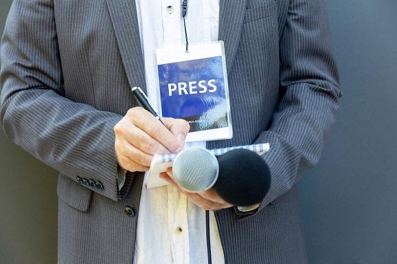 Novinář s kartičkou Press a mikrofonem